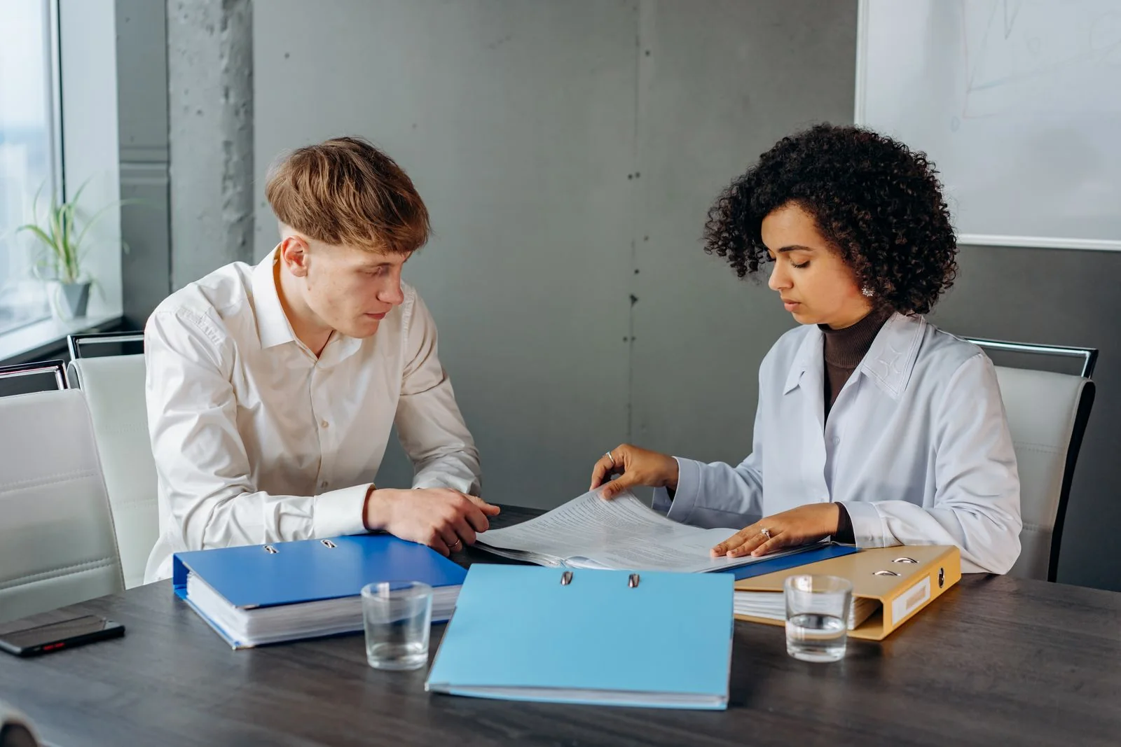 Two colleagues going through documents and folders together at a table